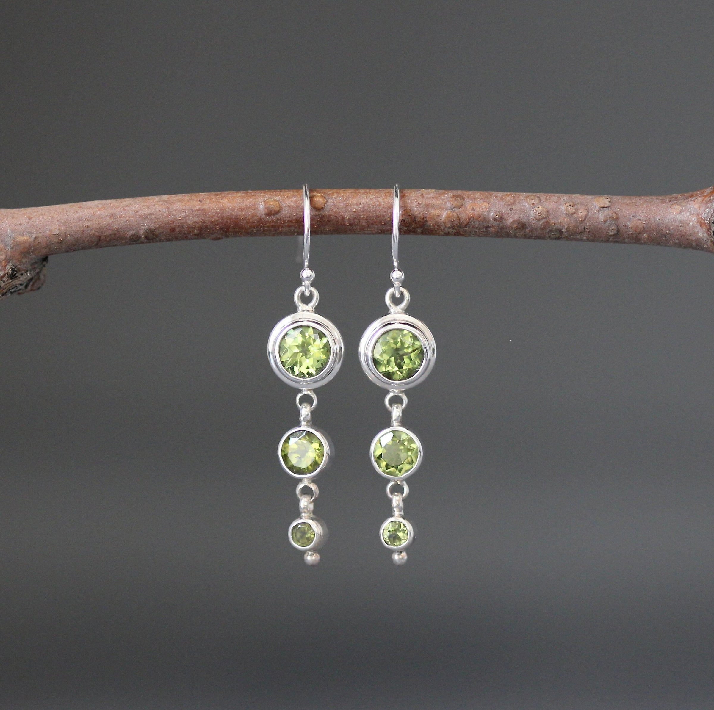 Sterling silver dangle earrings with three round green peridot stones
