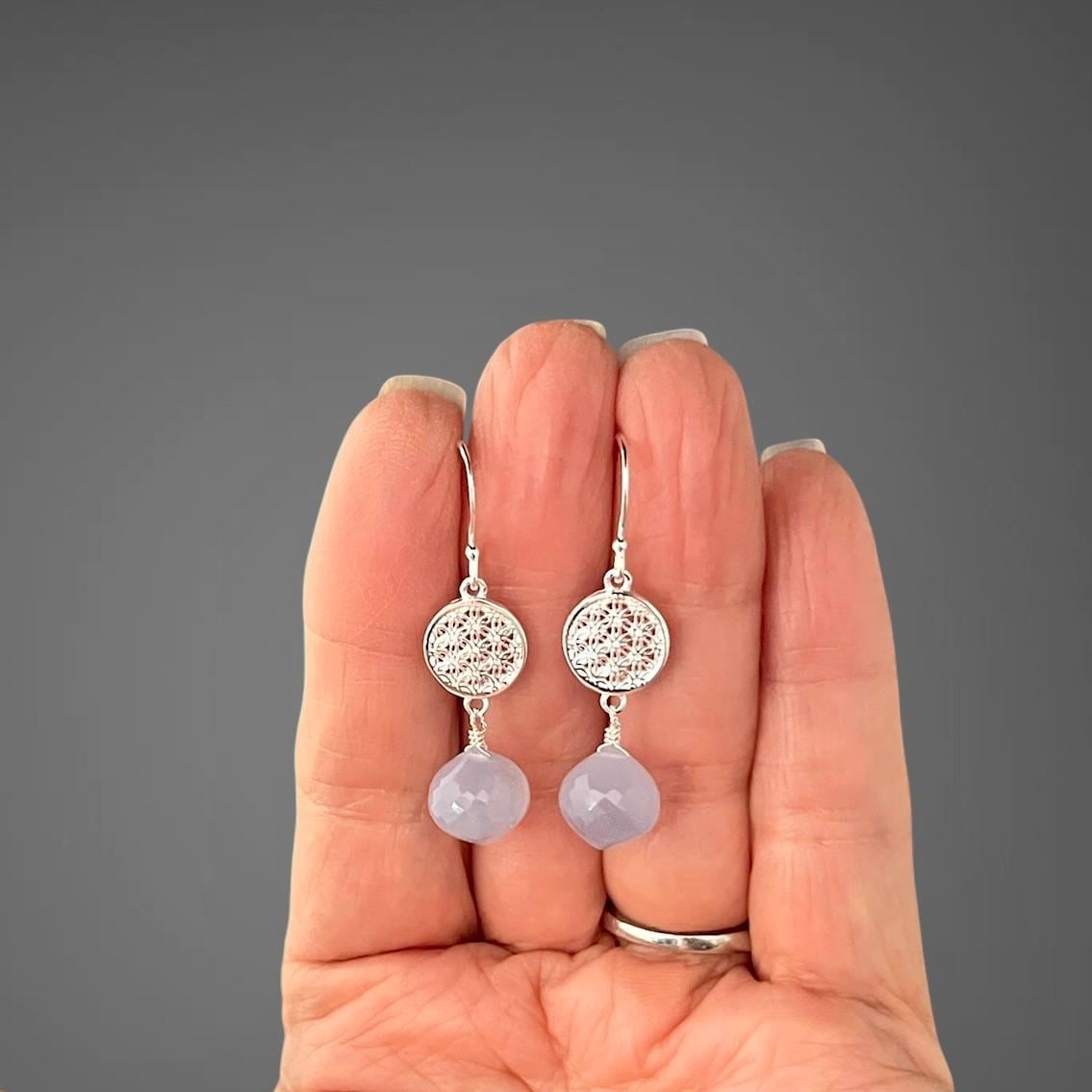 Sterling silver drop earrings with round filigree discs and blue chalcedony drops, on hand