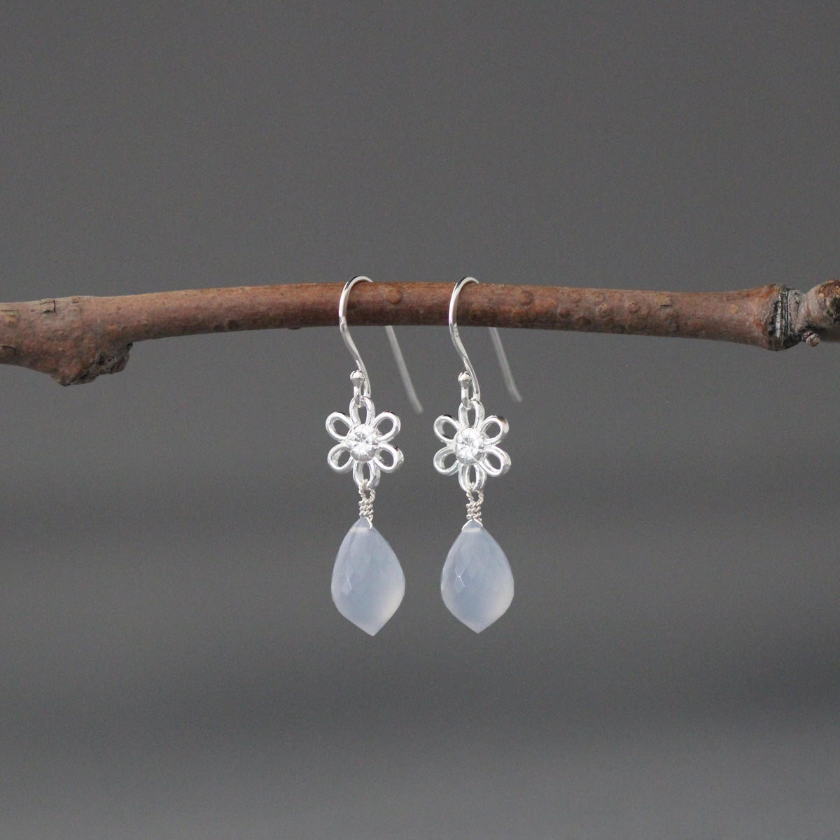 Pair of sterling silver flower dangle earrings with blue teardrop stones