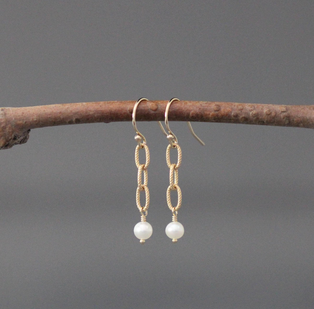 Gold hoop earrings with linked chain drops and small white freshwater pearls.