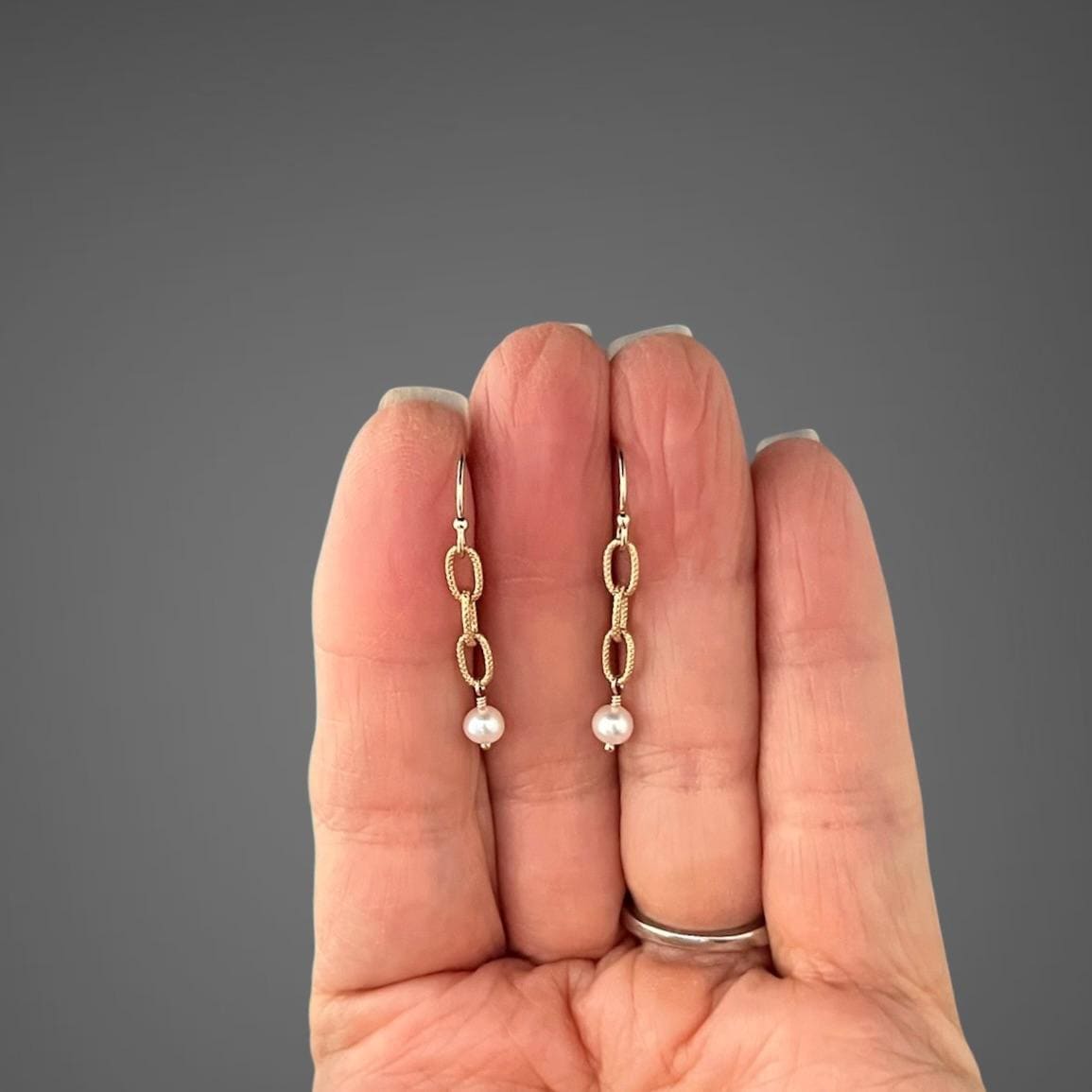 Gold chain-link freshwater pearl earrings hanging from leverback-style hooks.