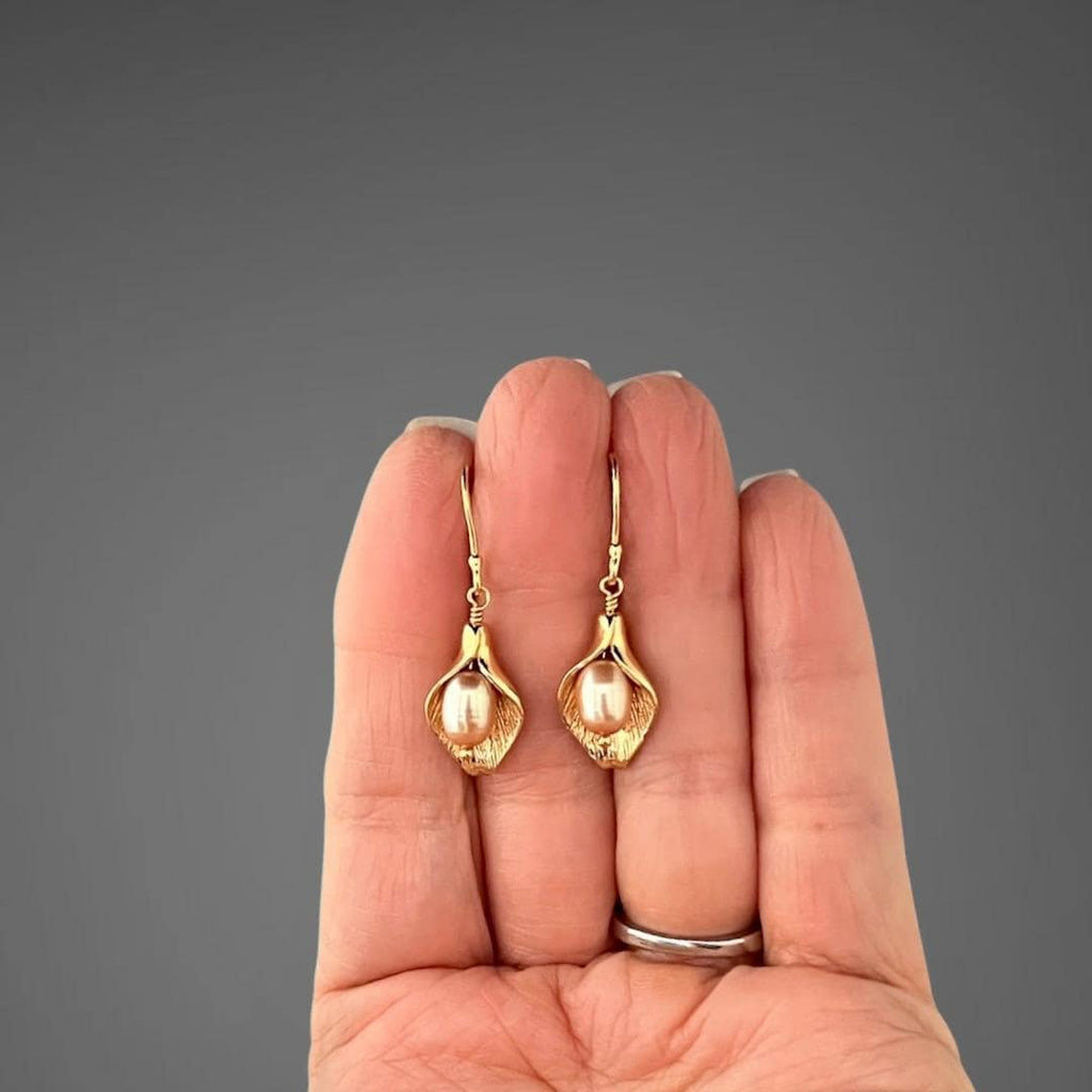 Peach freshwater pearl calla lily charm earrings, shown on hand for scale
