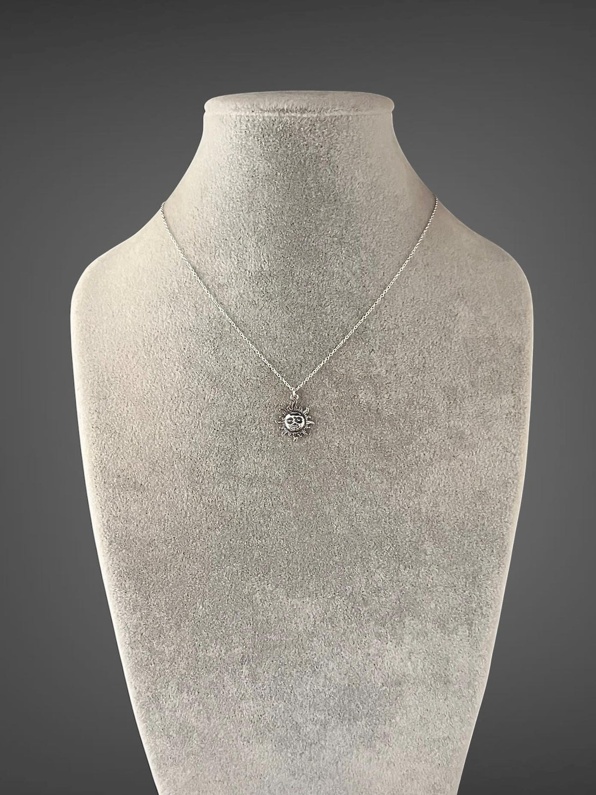Sterling silver sun pendant necklace on mannequin with small sun charm and chain
