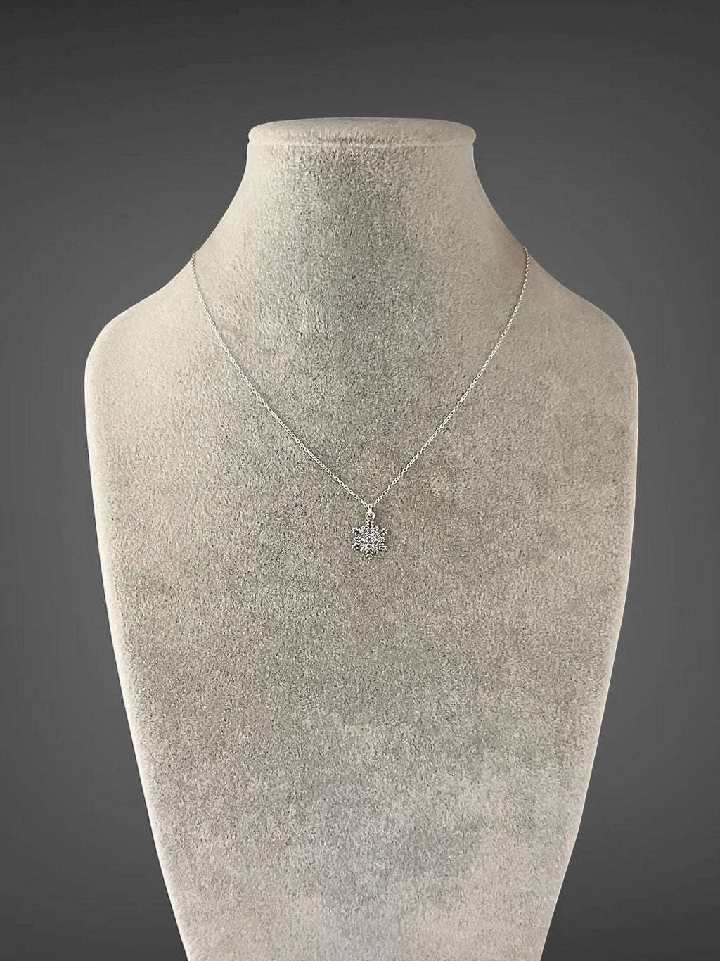 Sterling silver snowflake charm necklace worn on mannequin with single snowflake pendant