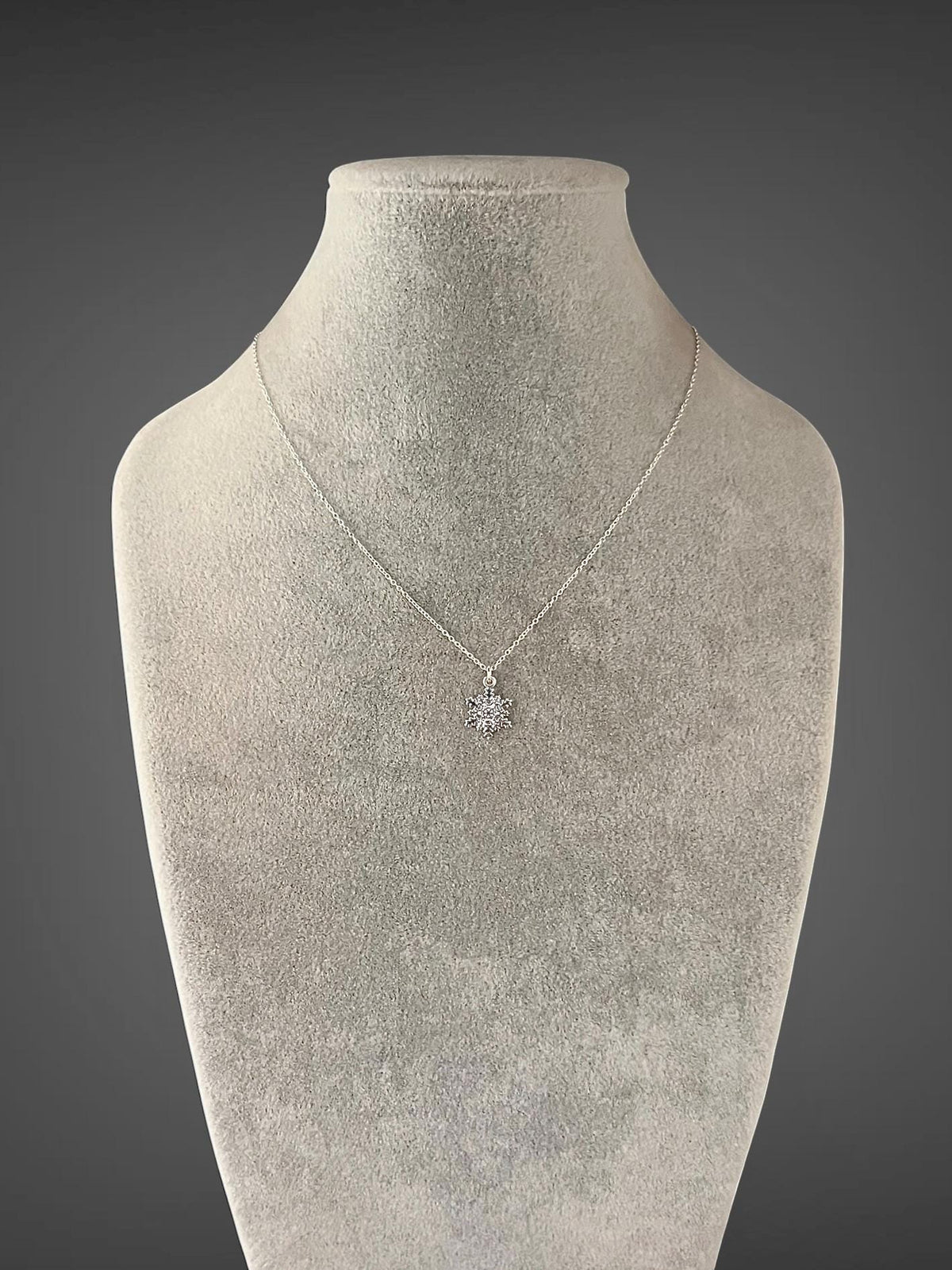 Sterling silver snowflake charm necklace worn on mannequin with single snowflake pendant
