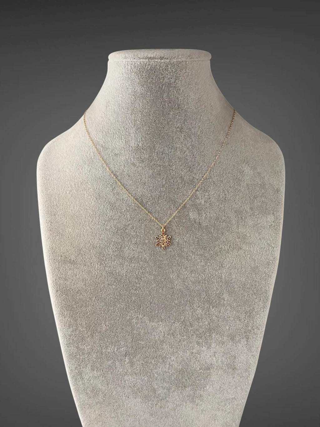 Gold snowflake pendant necklace displayed on a full bust