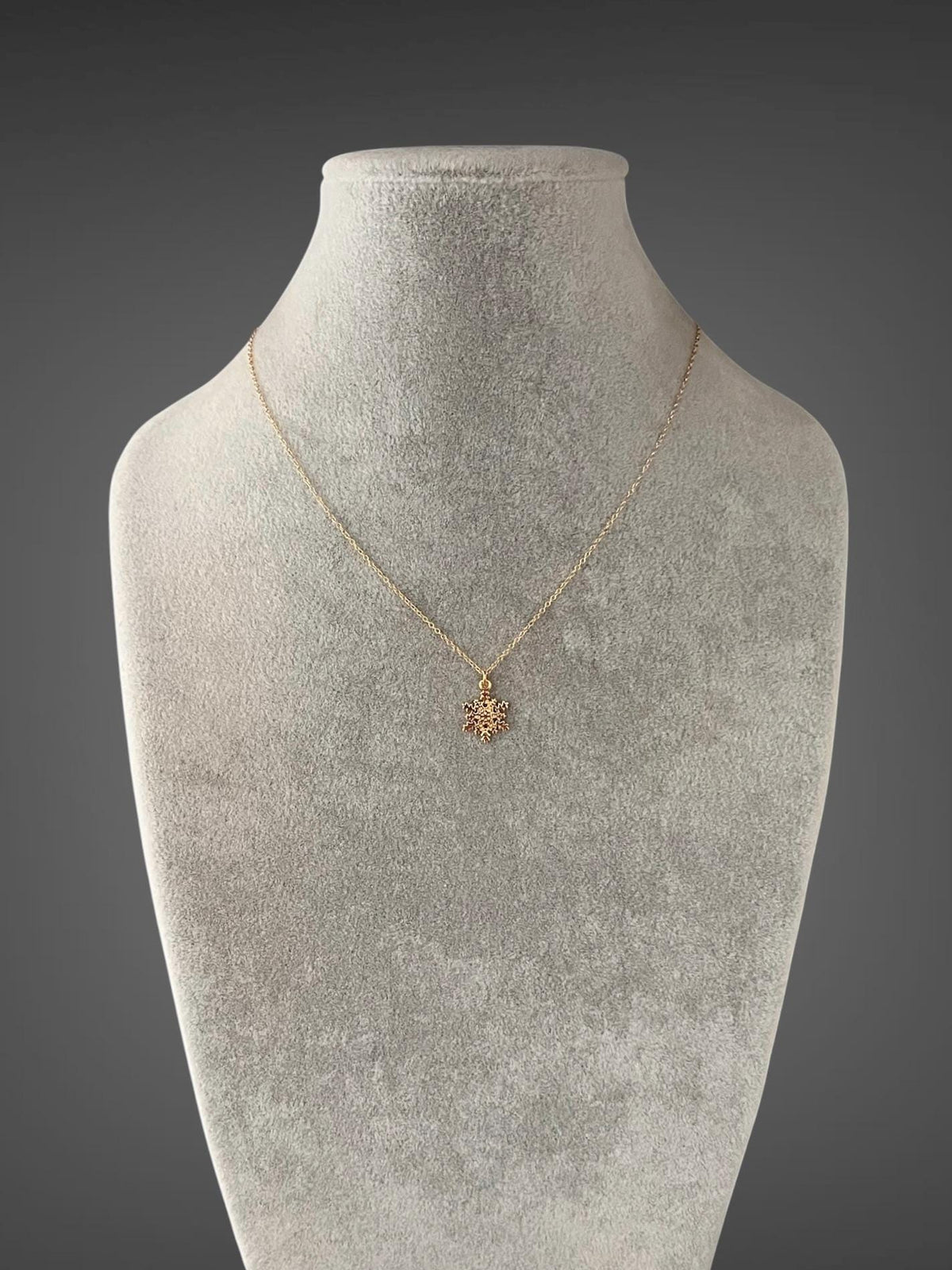 Gold snowflake pendant necklace displayed on a full bust