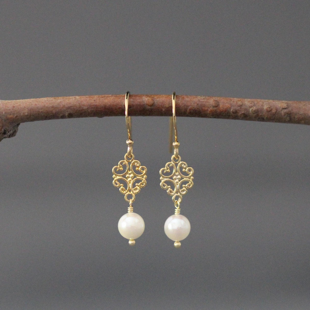 Close view of gold vermeil filigree earrings with dangling white pearls