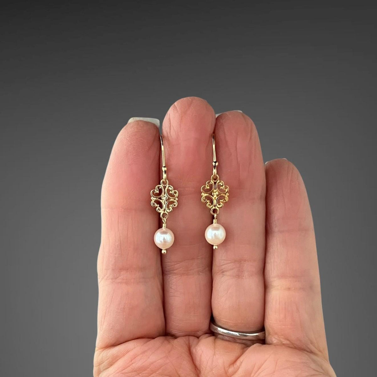 Gold vermeil link earrings with white pearls, shown against a hand for scale