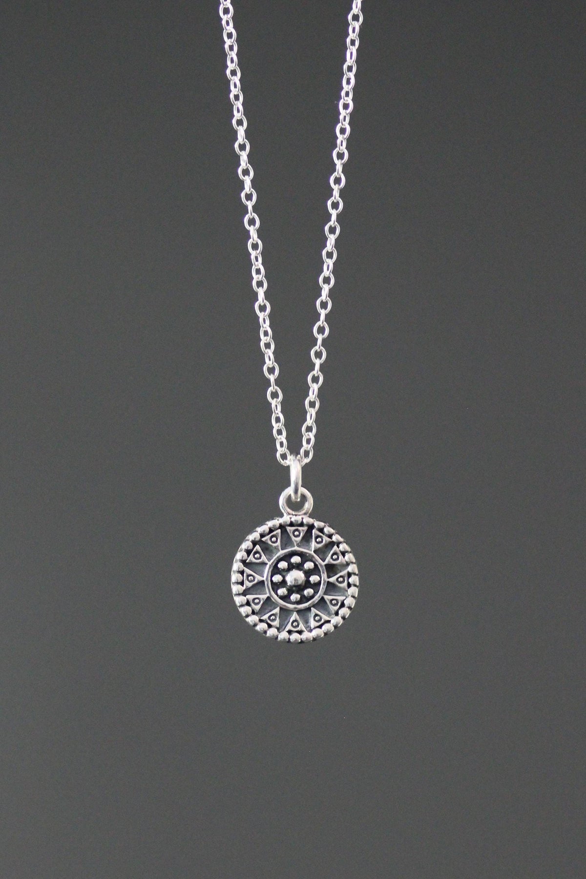 Sterling silver medallion charm necklace with an ornate round pendant and fine chain