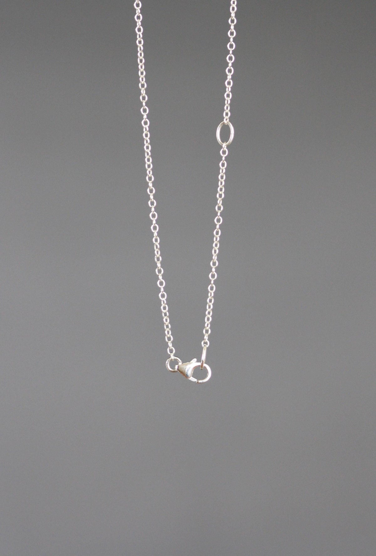 Sterling silver chain necklace with a close view of its clasp and adjustment ring