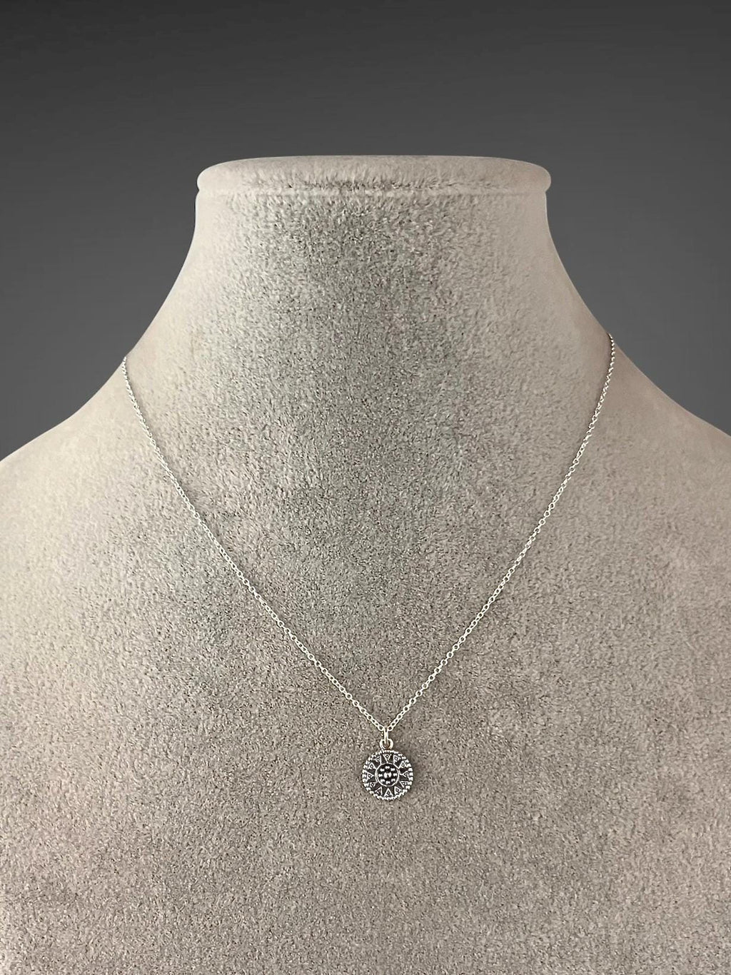 Sterling silver medallion necklace displayed on a bust, with a small round pendant