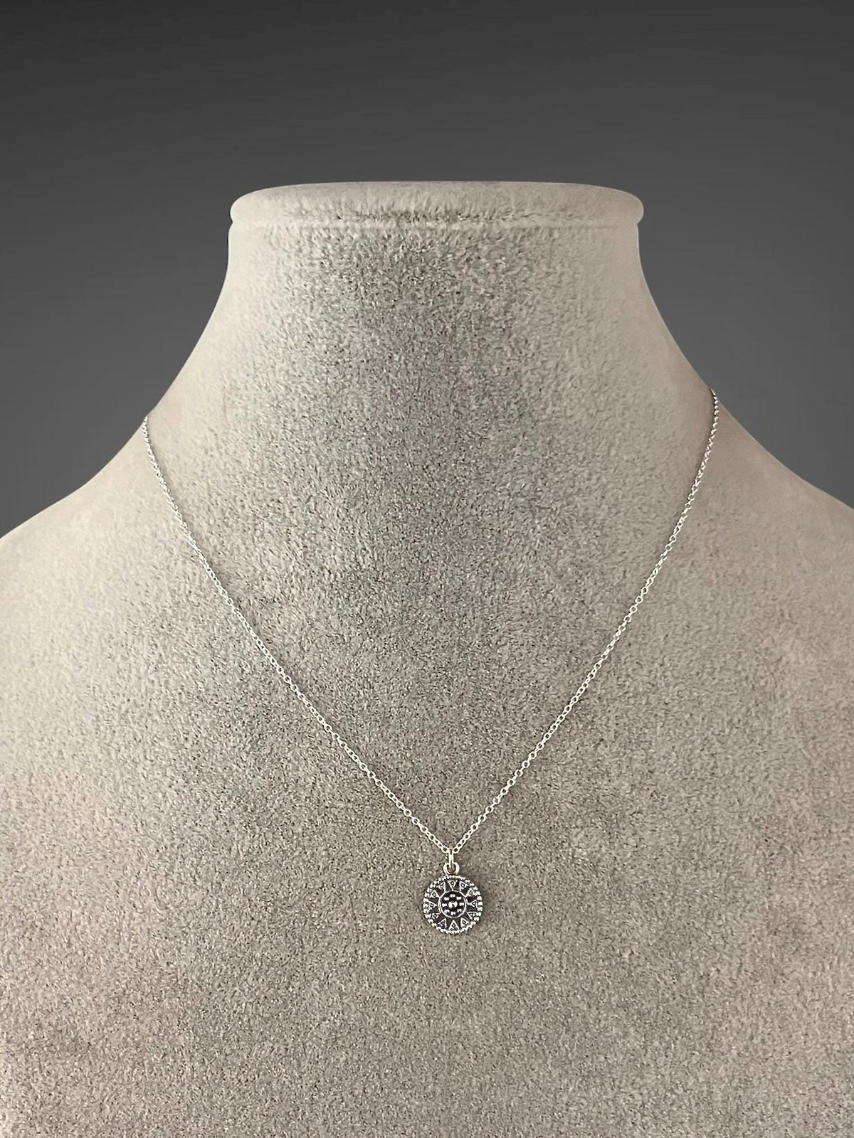 Sterling silver medallion necklace displayed on a bust, with a small round pendant