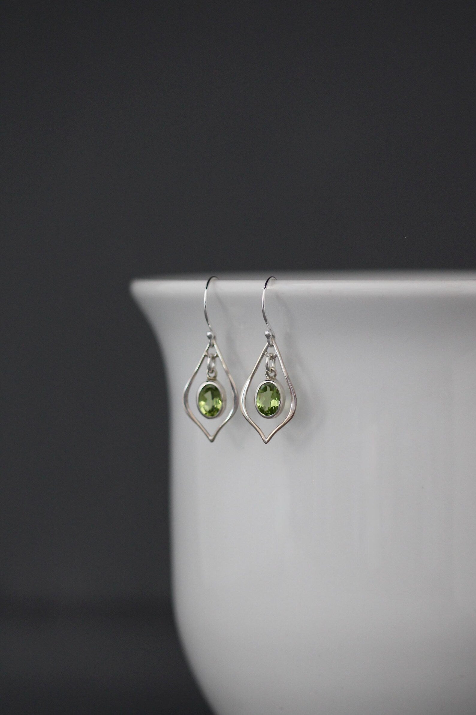 Silver drop earrings with oval green peridot in teardrop frames