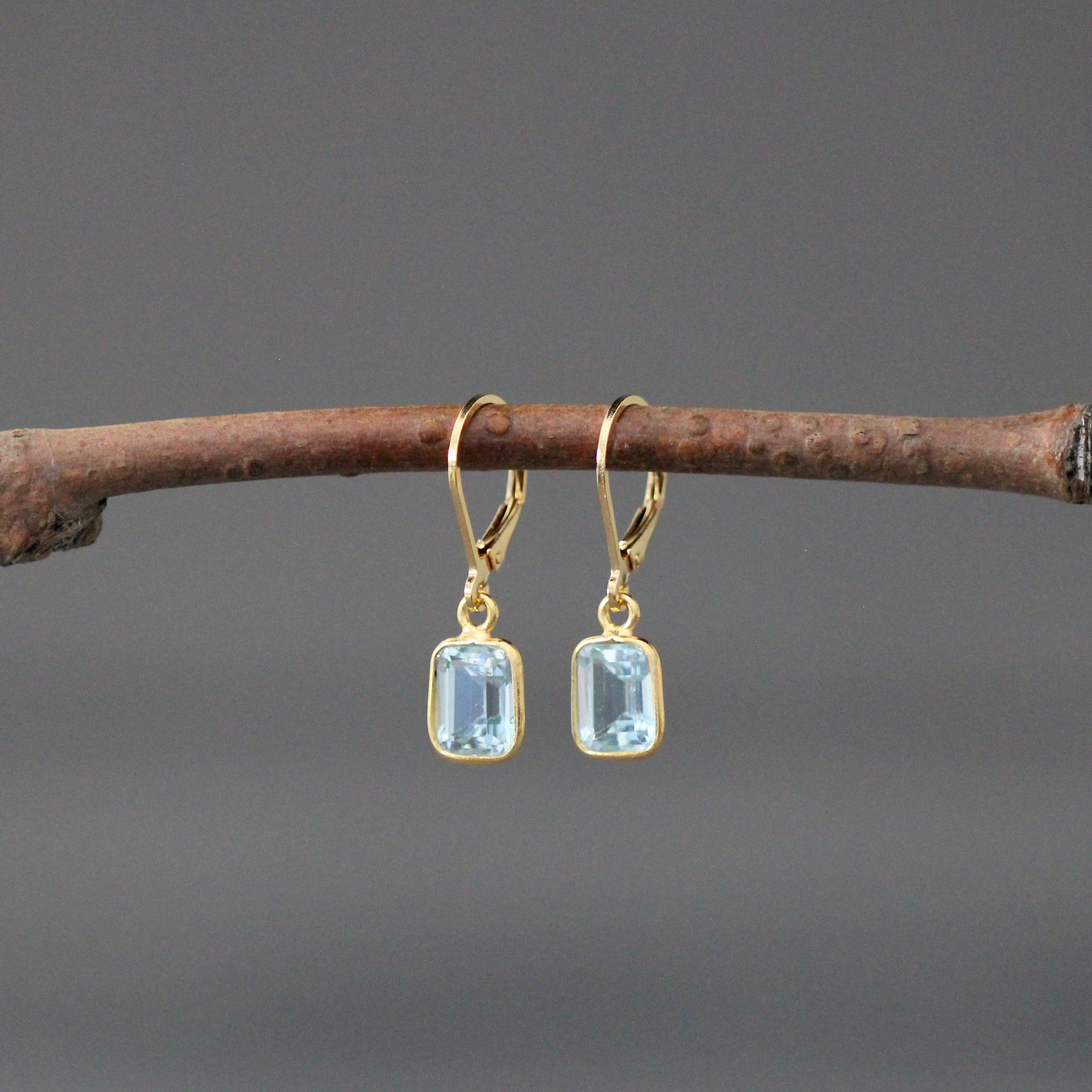 Gold vermeil leverback earrings with two light blue emerald-cut stone charms