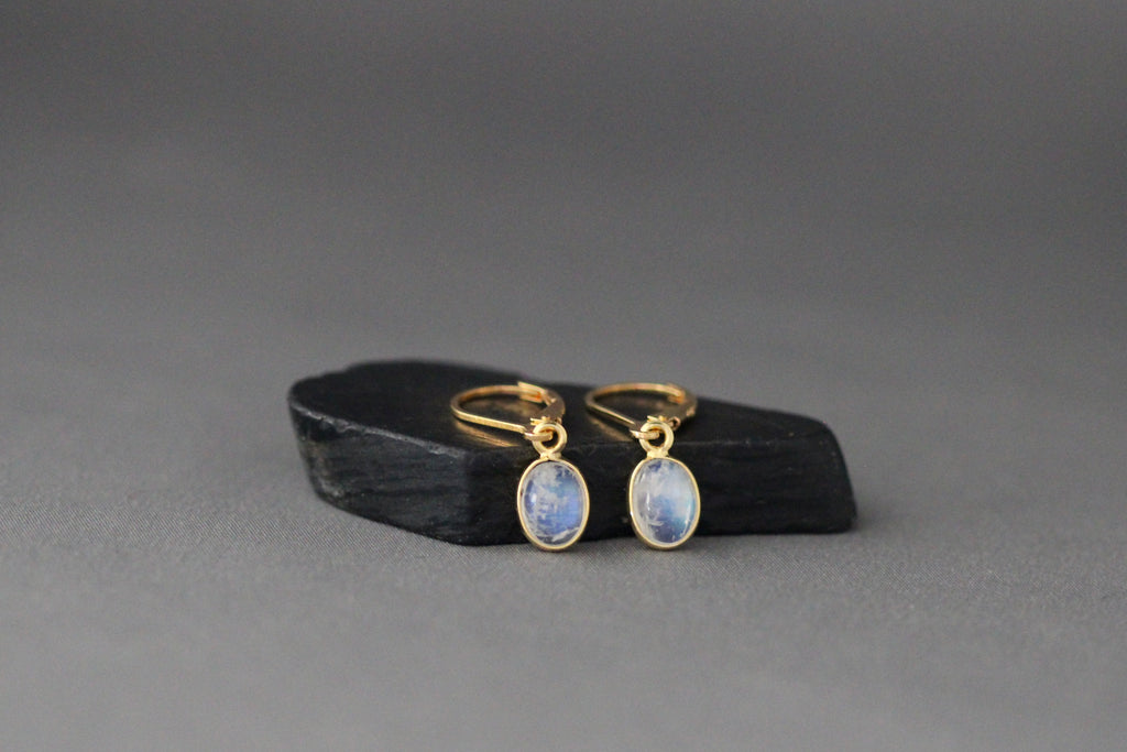 Gold leverback earrings featuring oval blue moonstone cabochon bezel drops