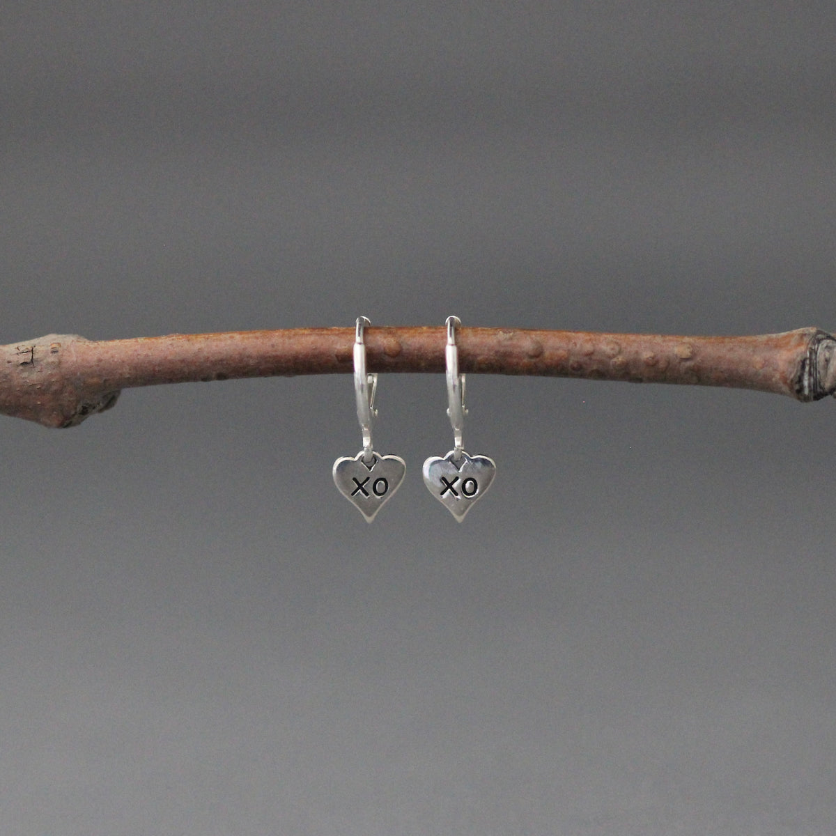 XO heart charm earrings on small silver huggie hoops with leverback closures