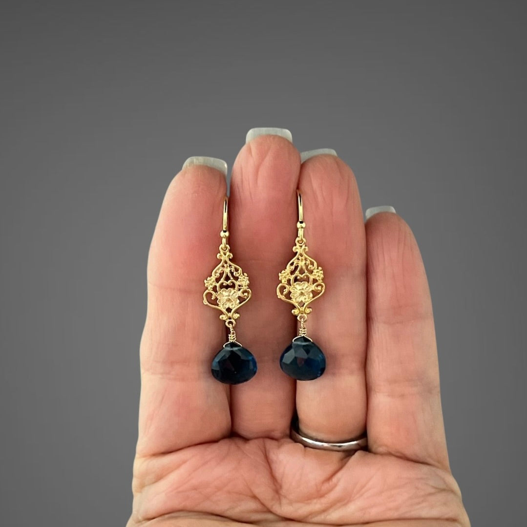 Gold vermeil filigree drop earrings with blue topaz stones, shown in hand