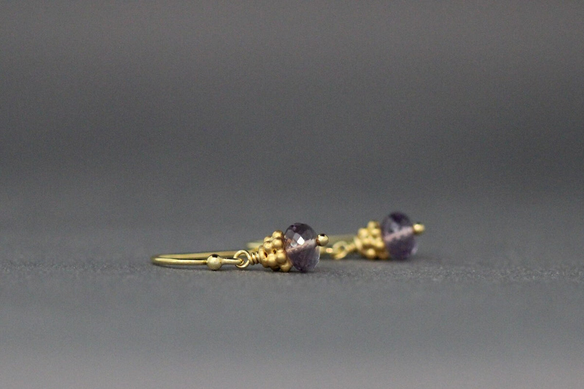 Side view of purple amethyst button drop earrings with gold-tone ear wire and beads