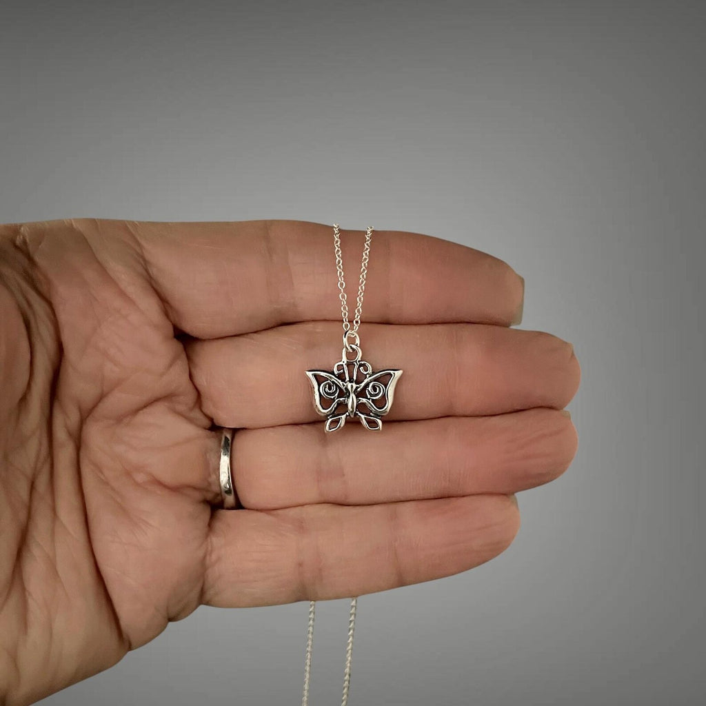 Sterling silver butterfly charm pendant necklace held in hand, winged charm centered