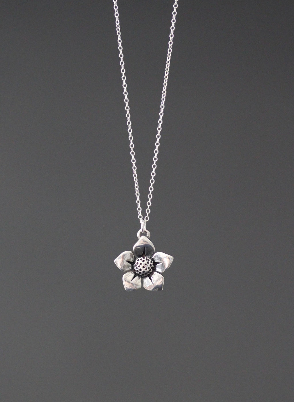 Sterling silver flower charm pendant on fine chain necklace, textured center flower design.