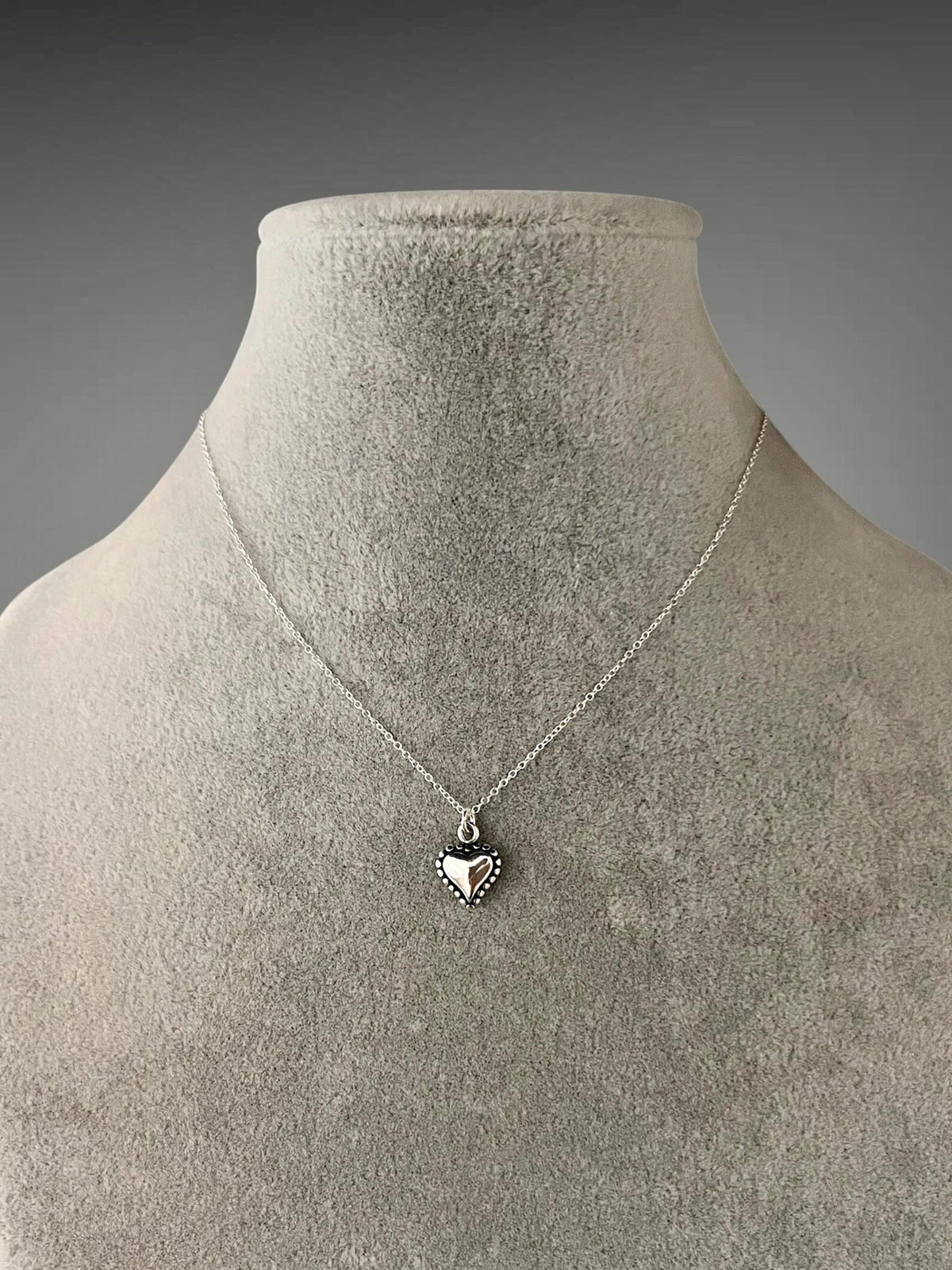 Sterling silver heart pendant necklace with small charm detail on thin chain