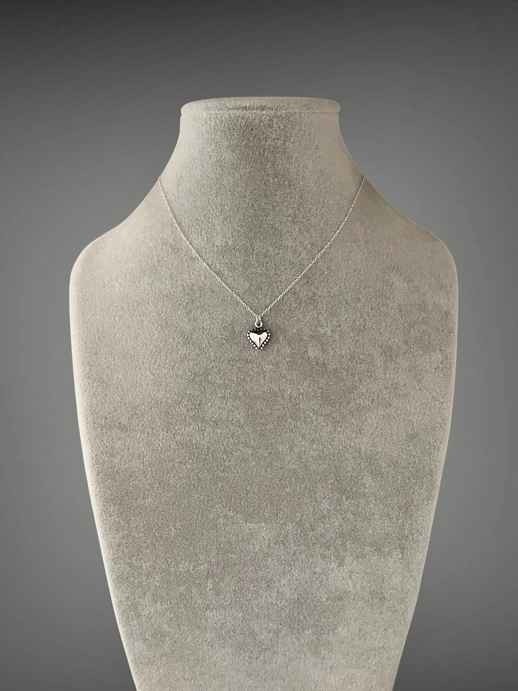Sterling silver heart pendant necklace resting on a thin chain