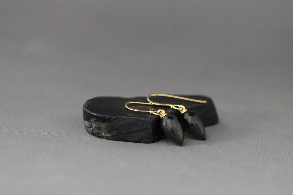Black stone with gold earrings on a gray background