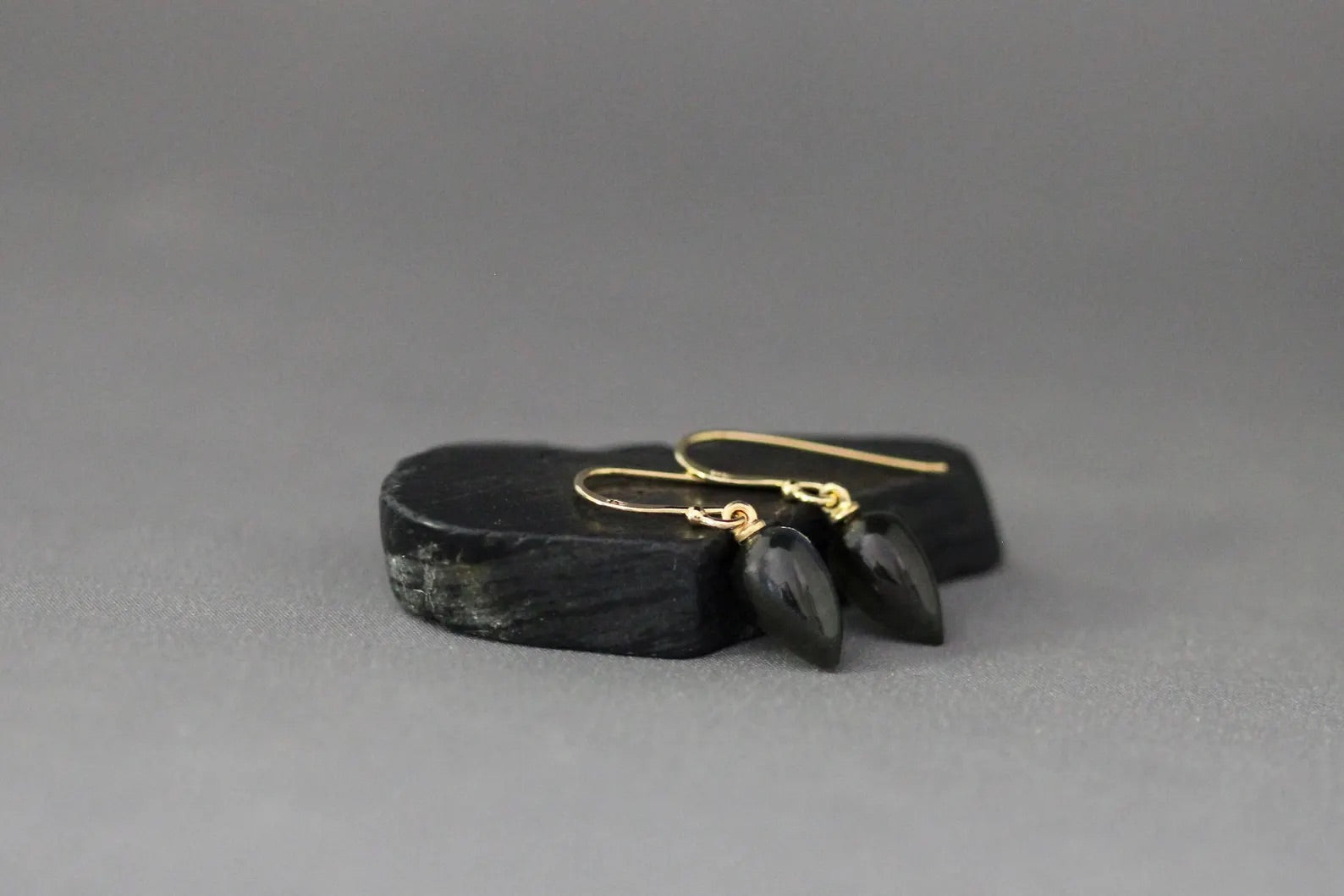 Black stone with gold earrings on a gray background