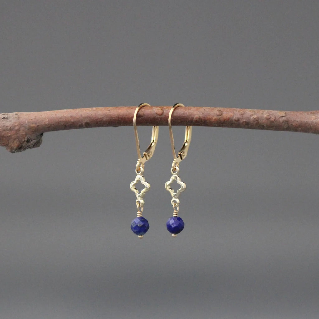 Gold hoop earrings with blue lapis bead dangles and small quatrefoil charms