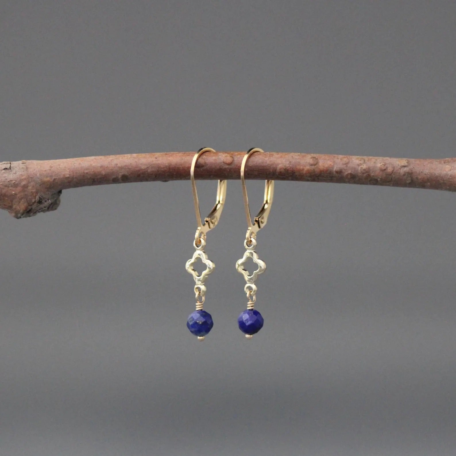 Gold hoop earrings with blue lapis bead dangles and small quatrefoil charms