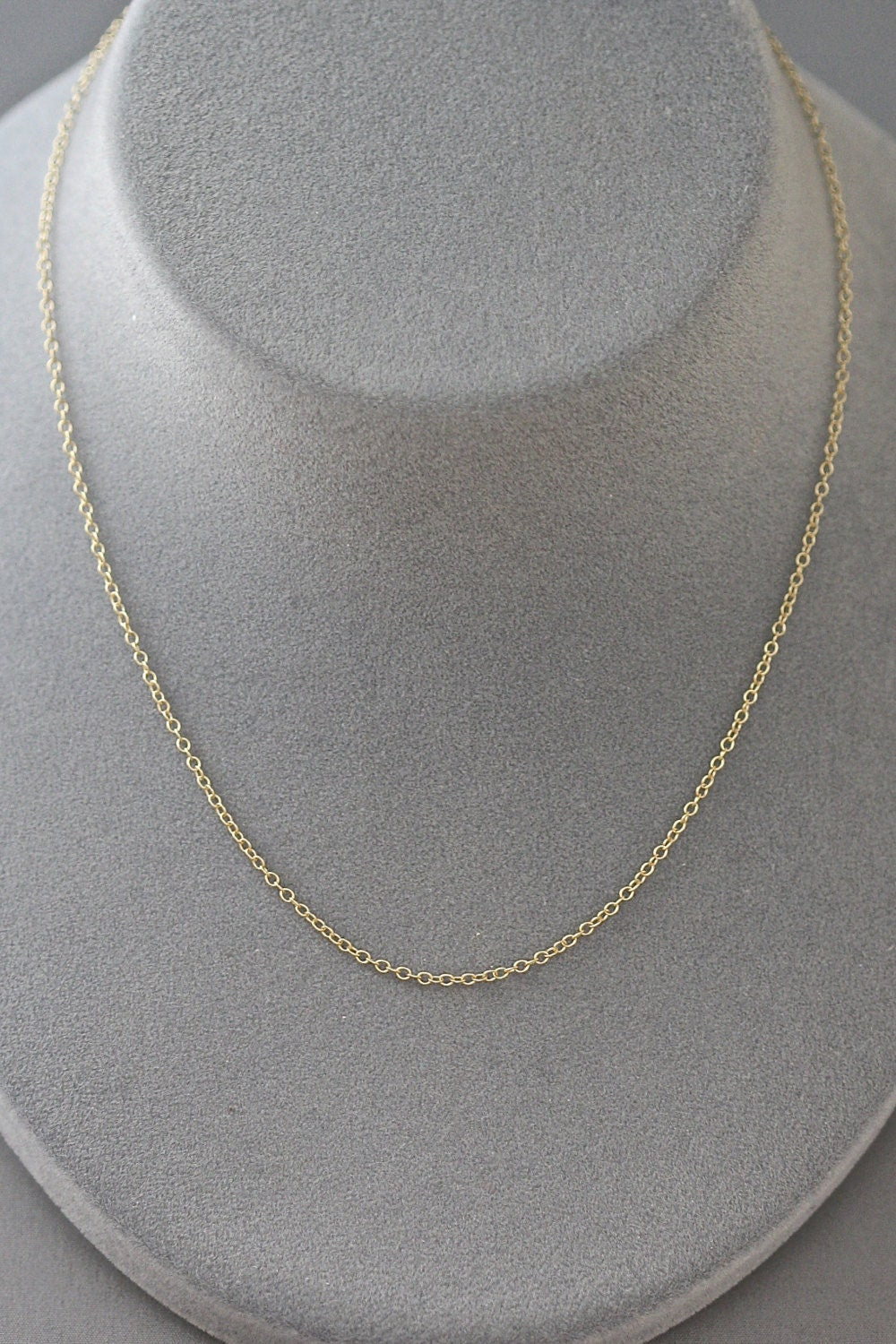 Gold chain necklace on a gray bust