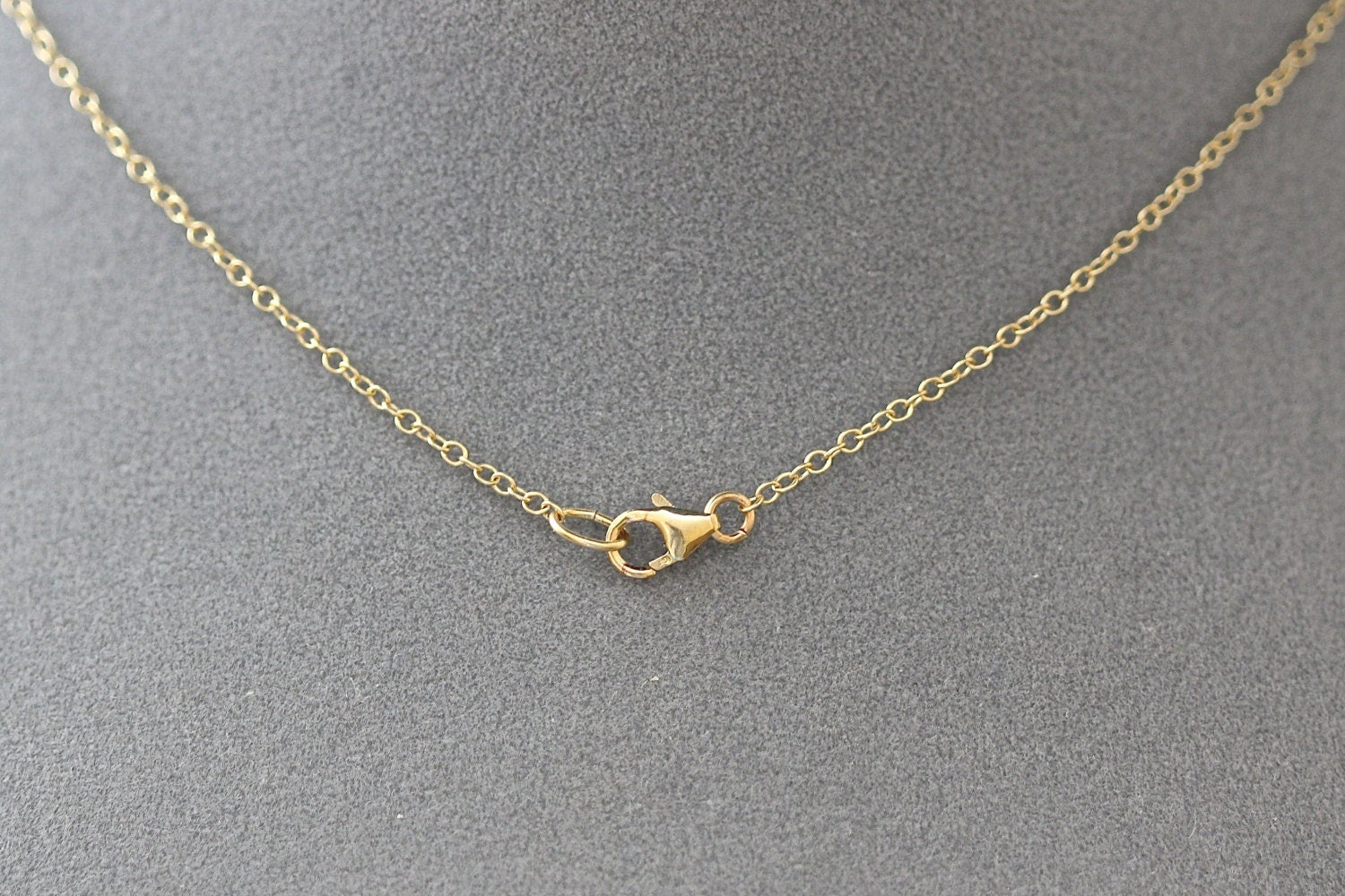 Gold necklace with clasp on a gray background