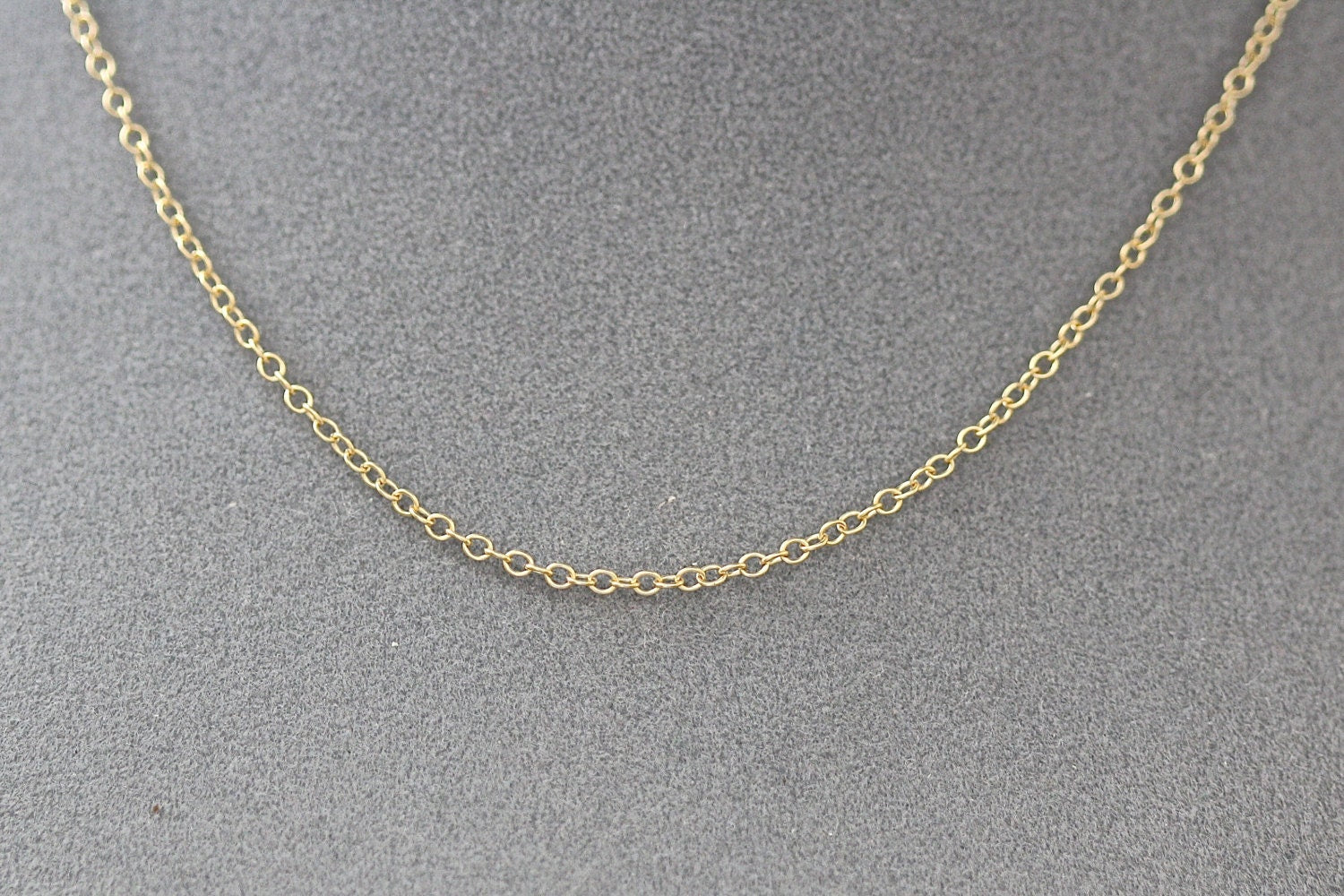 Gold chain necklace on a gray background