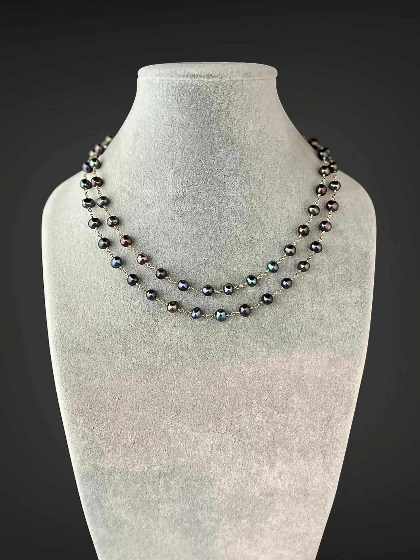 Multi-strand necklace of dark freshwater pearls with gold wire accents, short drape.