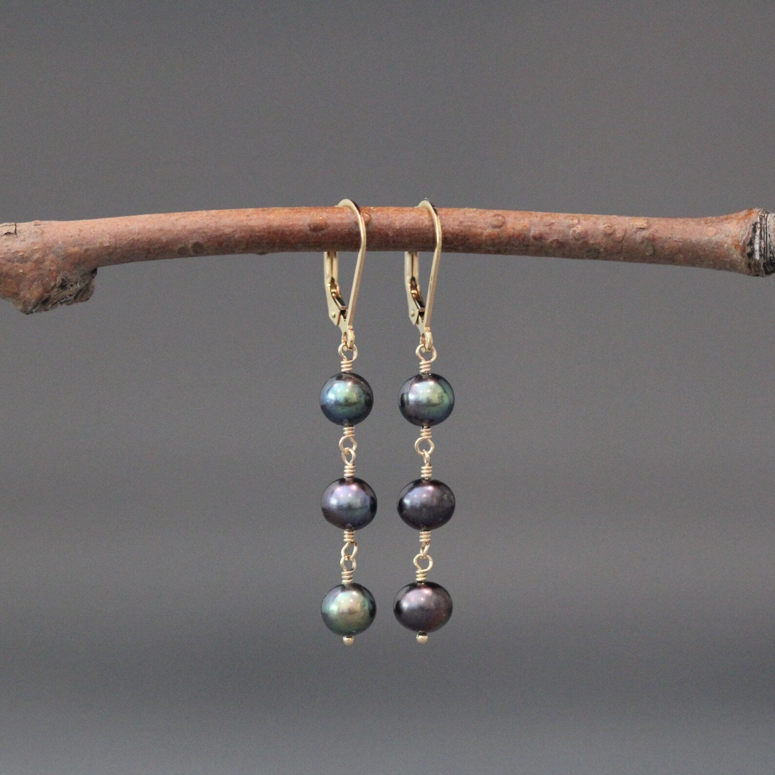 Gold hoop earrings with three dark freshwater pearls, wire-wrapped dangle drops.