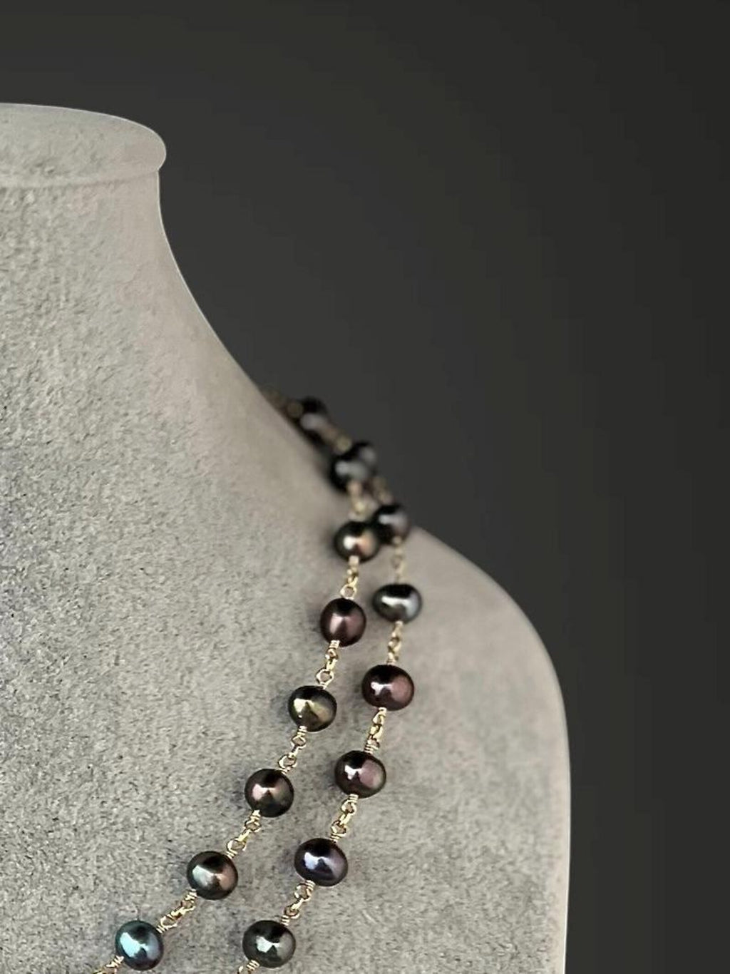 Detail of layered dark freshwater pearl necklace with gold wire links and loops.