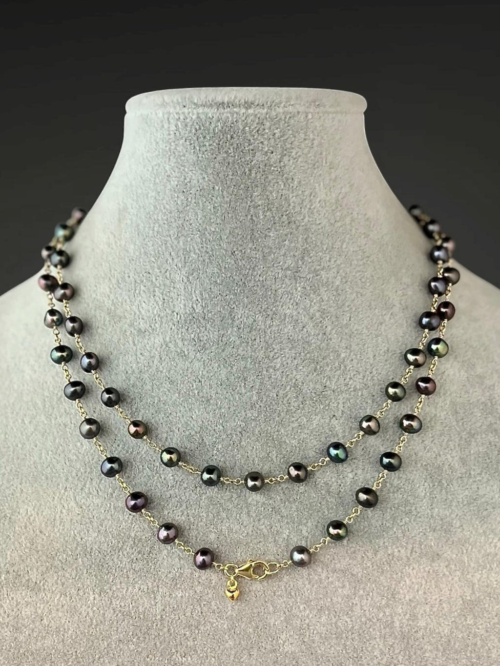 Layered dark freshwater pearl necklace with gold chain connectors and wire-wrapped beads.