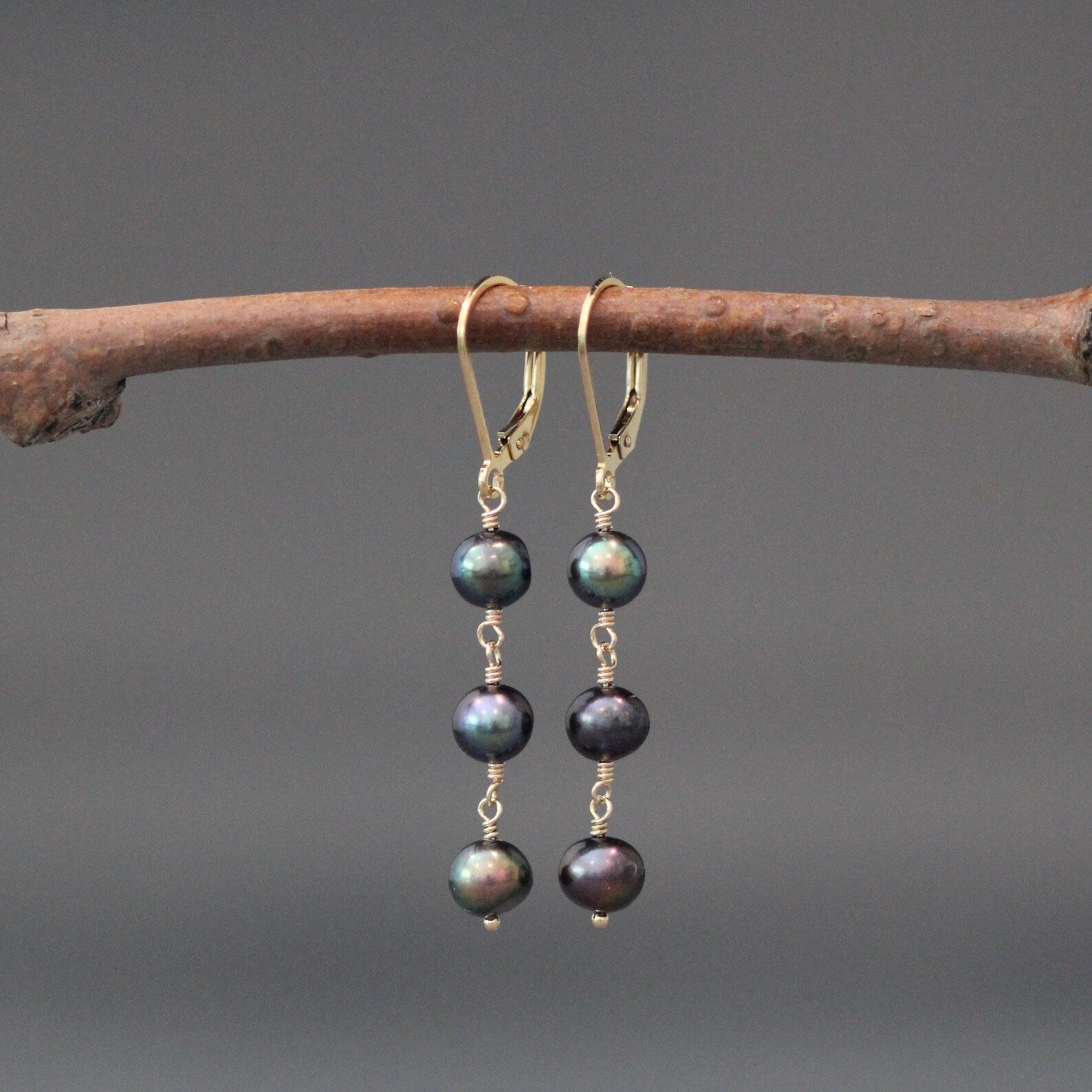 Gold hoop earrings with three dark freshwater pearls, wire-wrapped dangles.