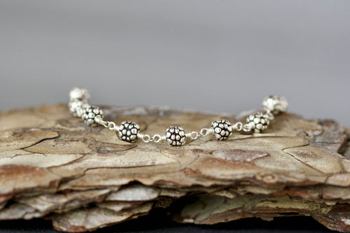 Sterling silver beaded bracelet with round textured beads laid on stone