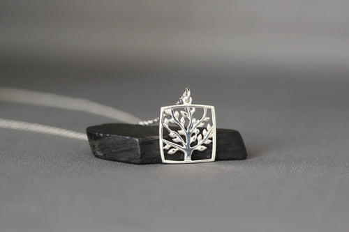 Silver square pendant tree-of-life charm on a short chain, resting on display surface