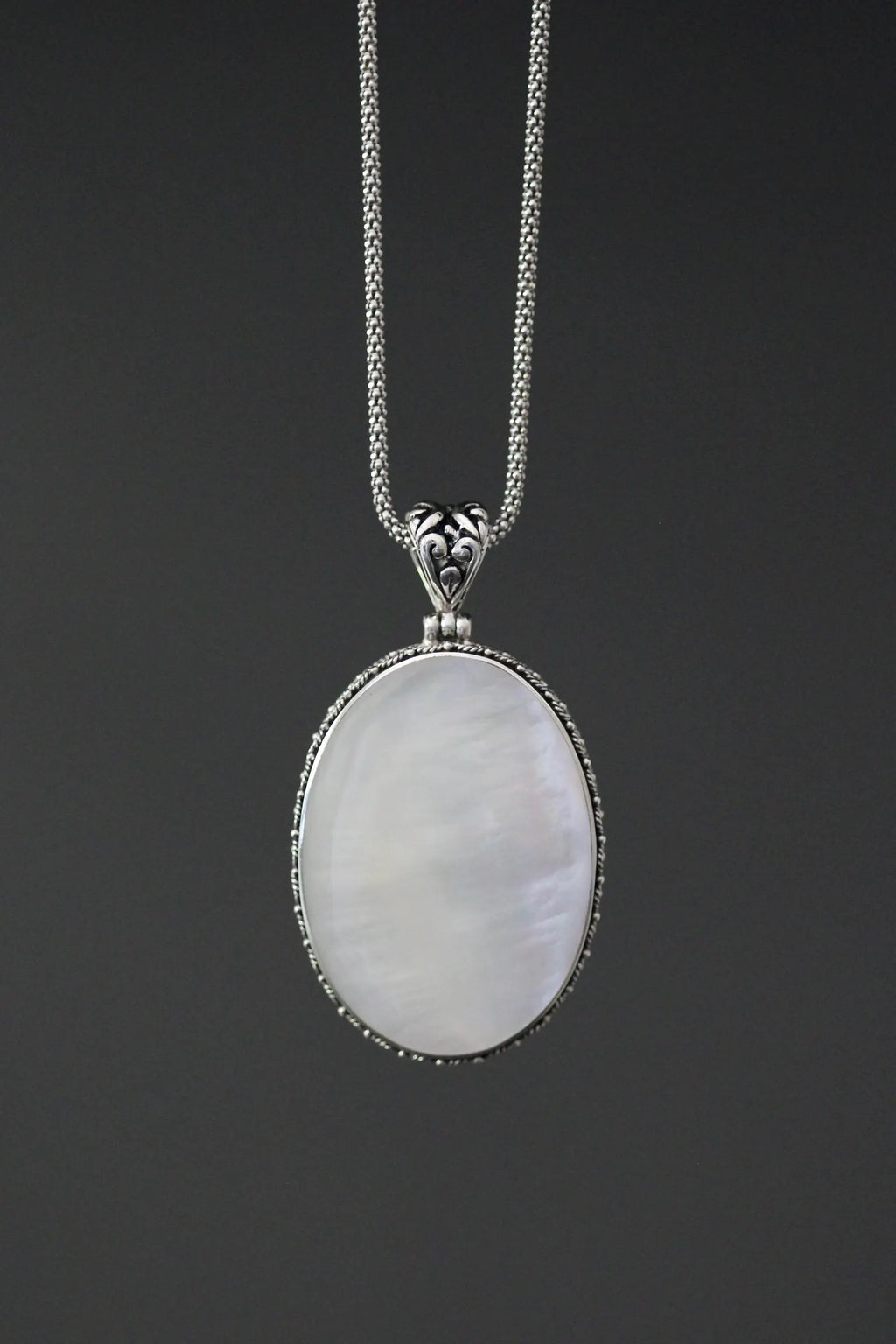 Close up image of a white mother of pearl and silver pendant necklace