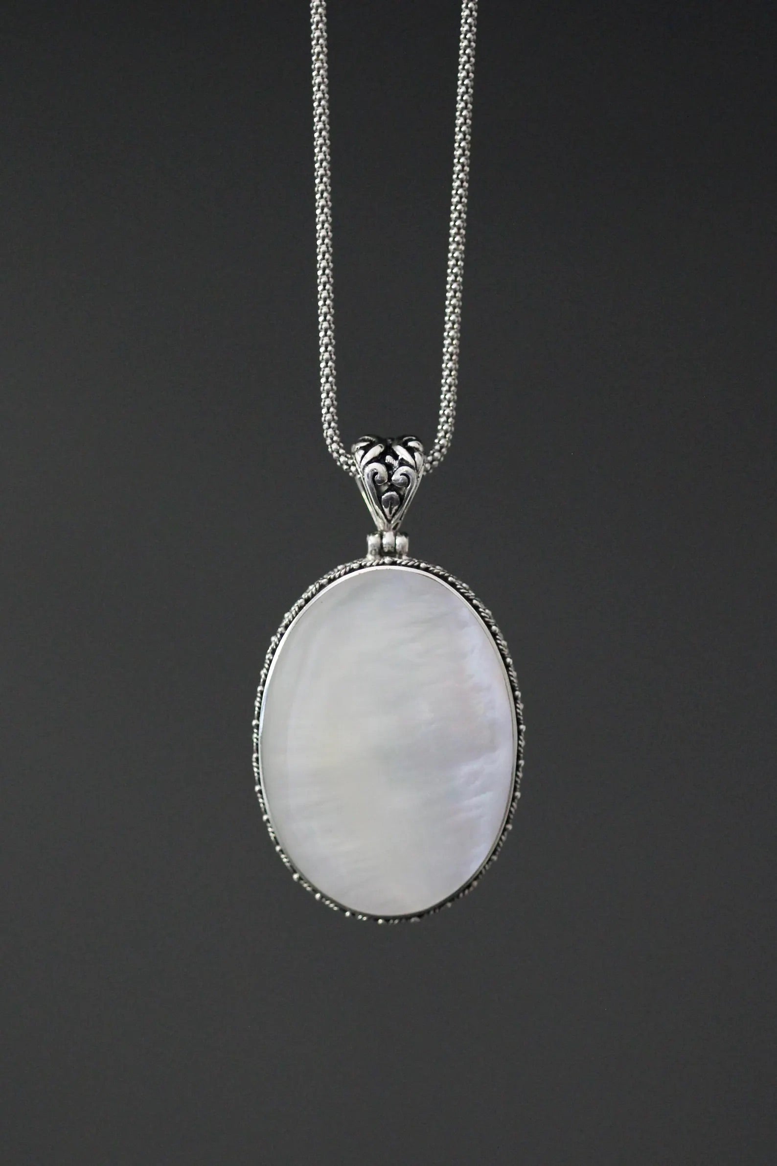 Close up image of a white mother of pearl and silver pendant necklace