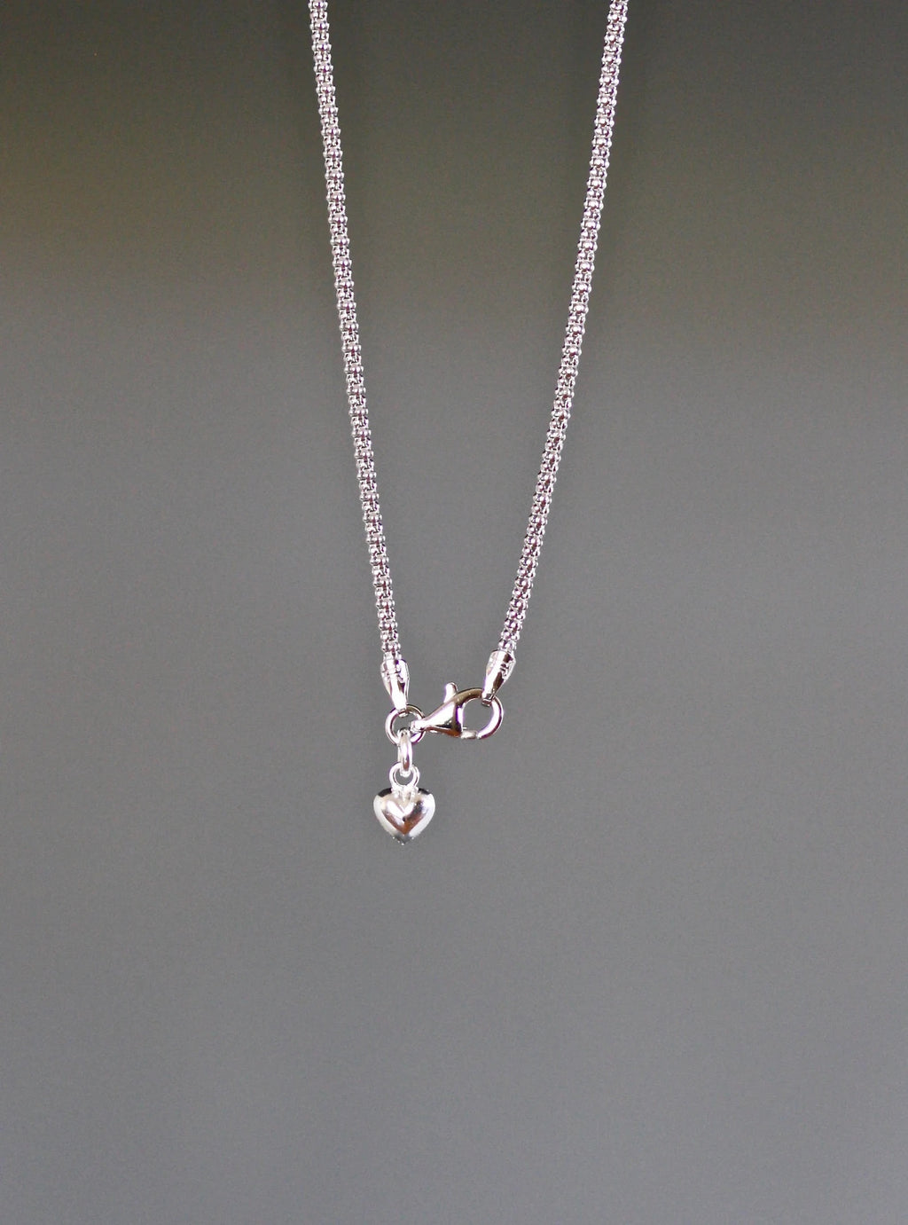 Close up image of a necklace clasp against a gray backdrop