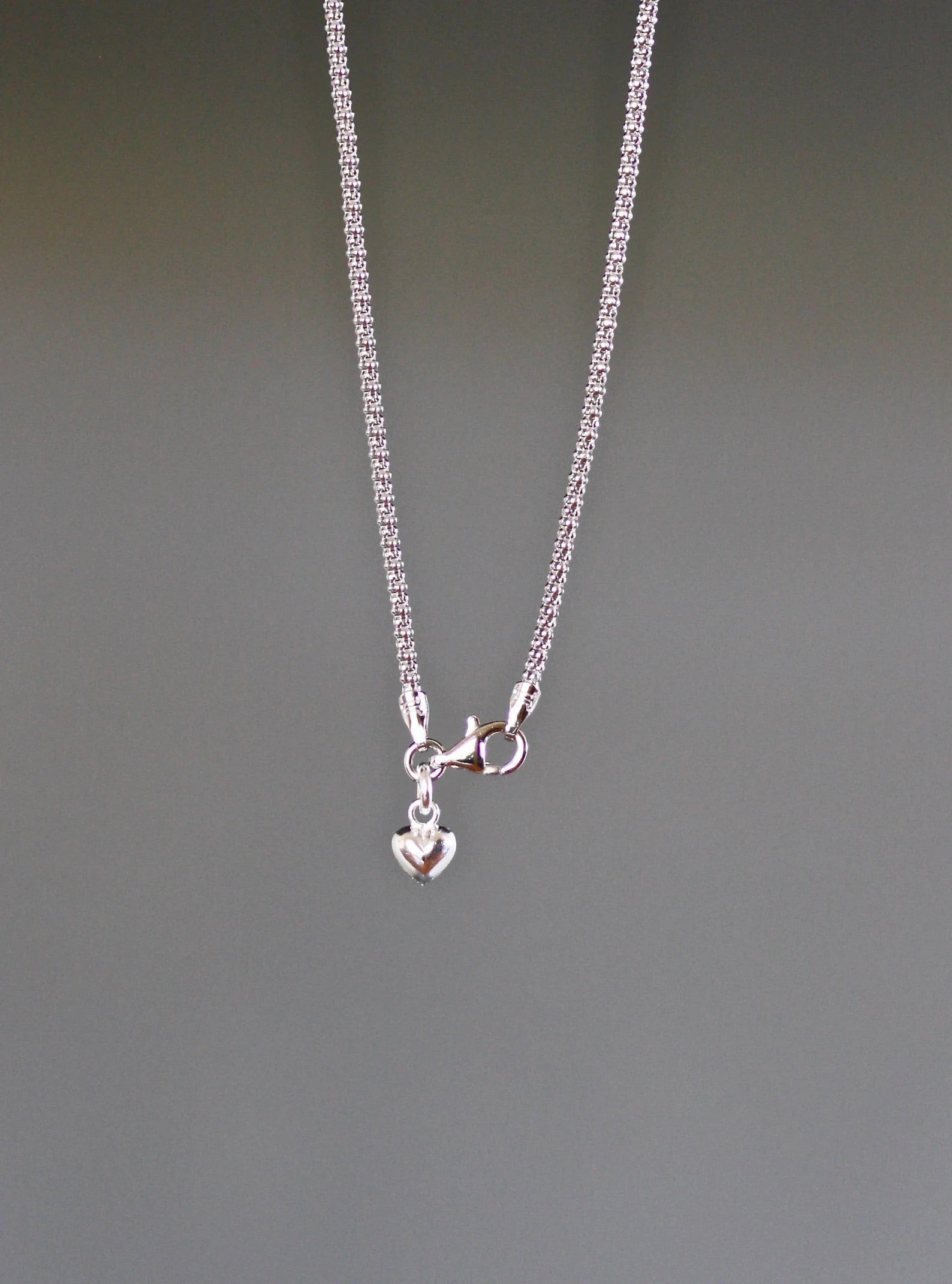 Close up image of a necklace clasp against a gray backdrop