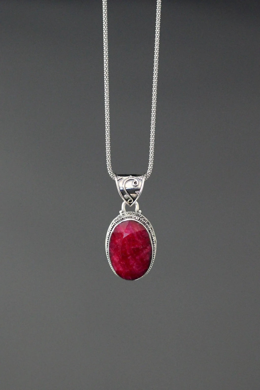 Sterling silver oval ruby-red gemstone pendant with ornate frame on chain