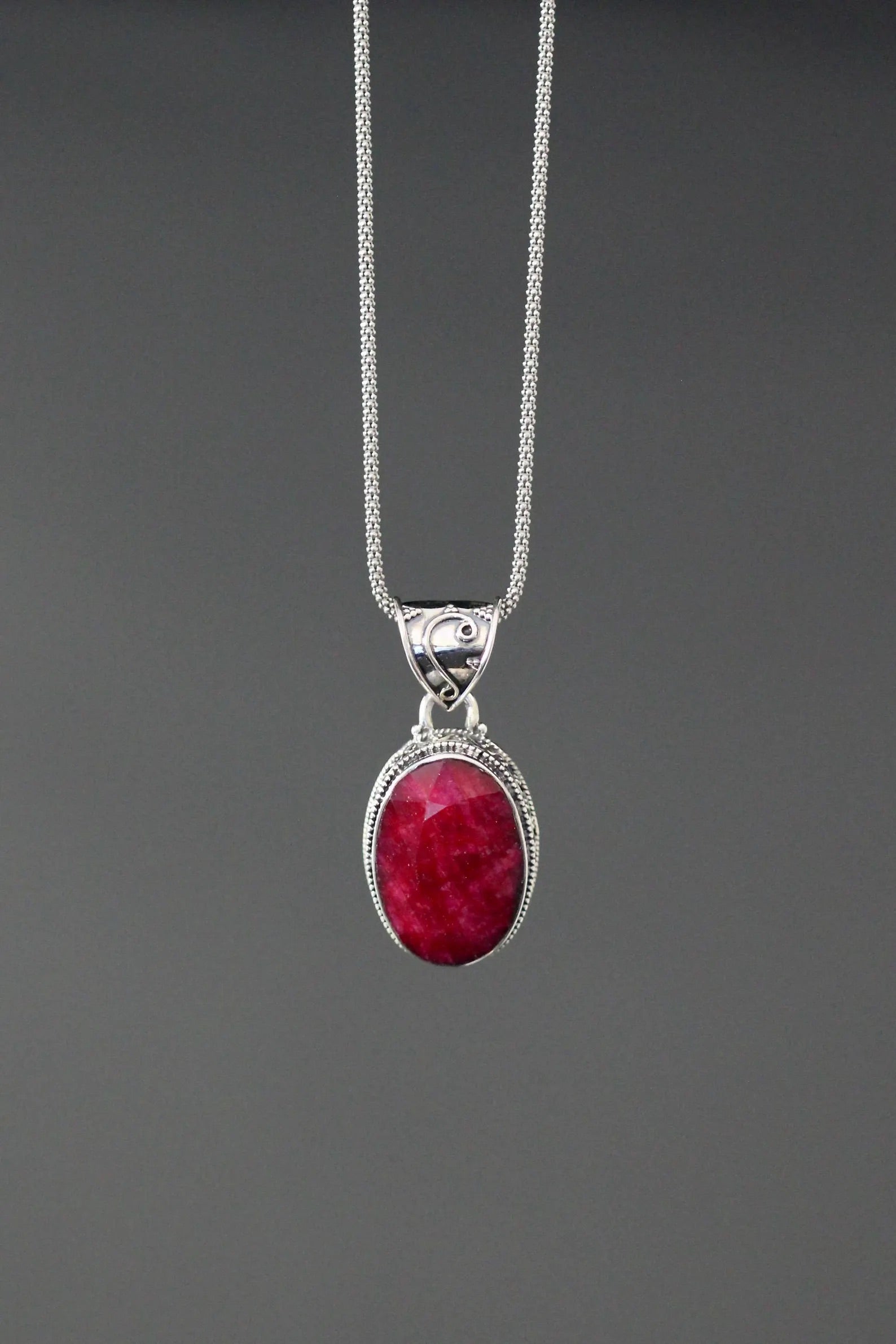 Sterling silver oval ruby-red gemstone pendant with ornate frame on chain