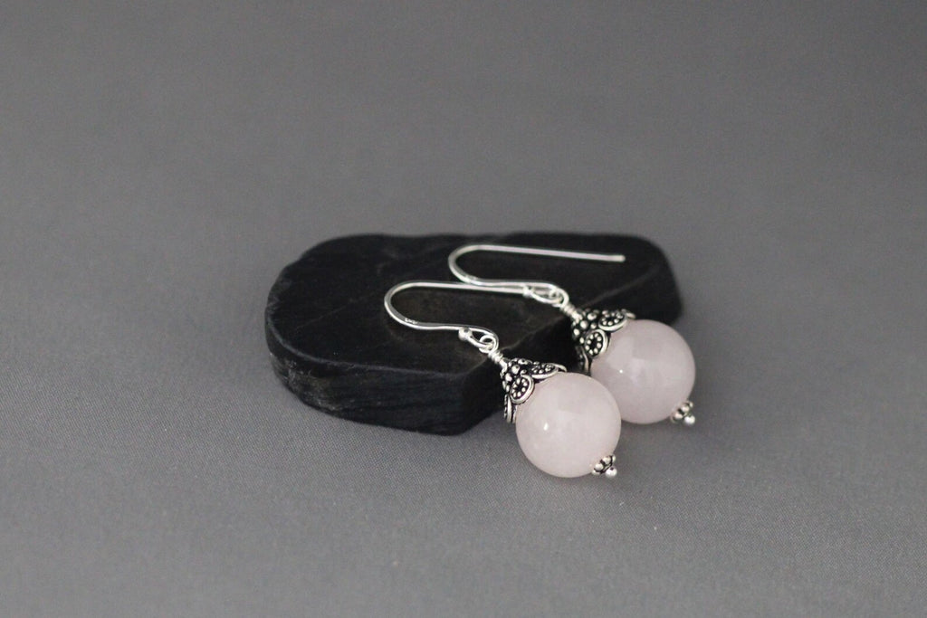 Rose quartz and silver earrings against a gray backdrop