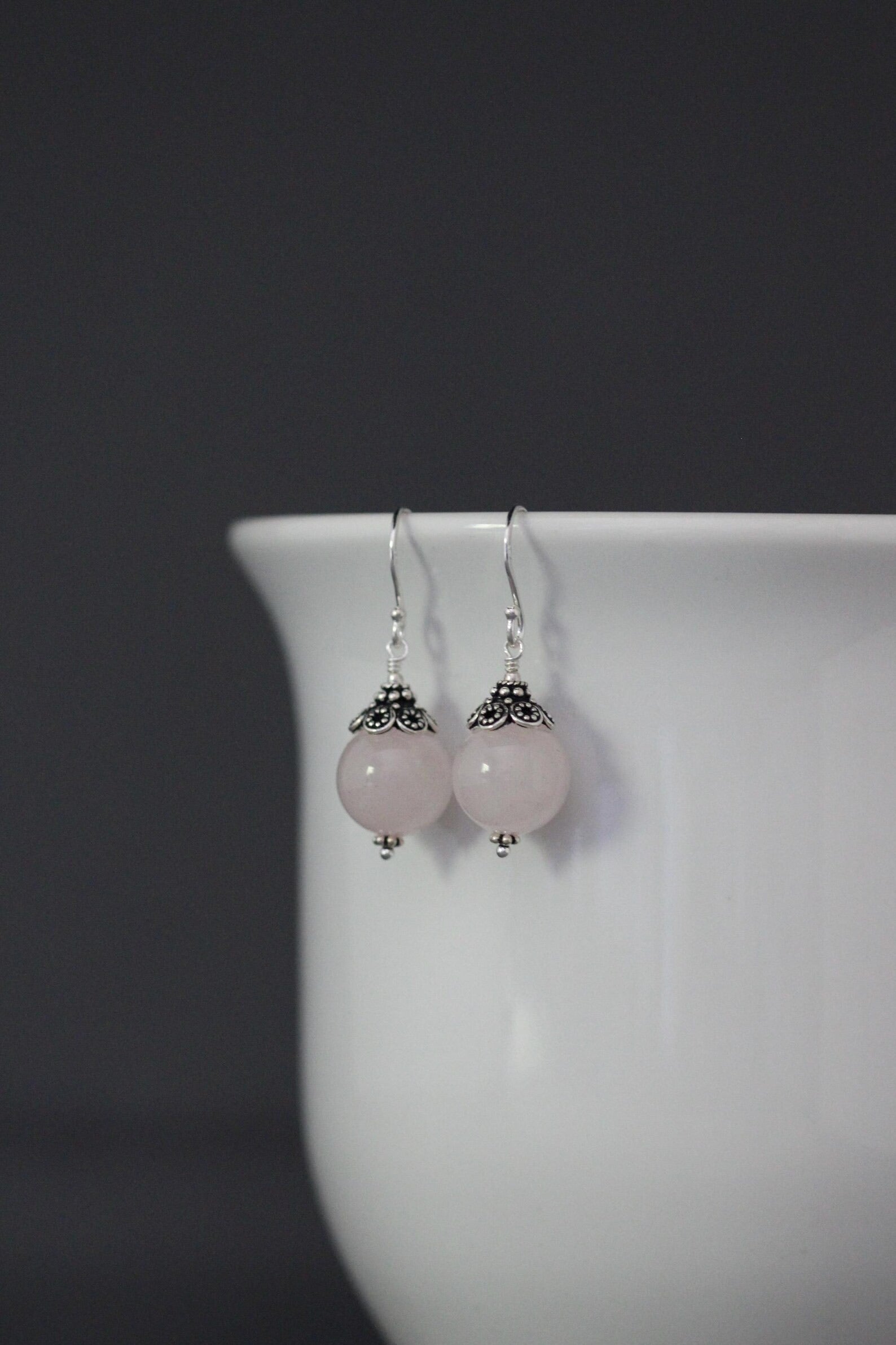 Rose quartz and silver earrings against a gray backdrop