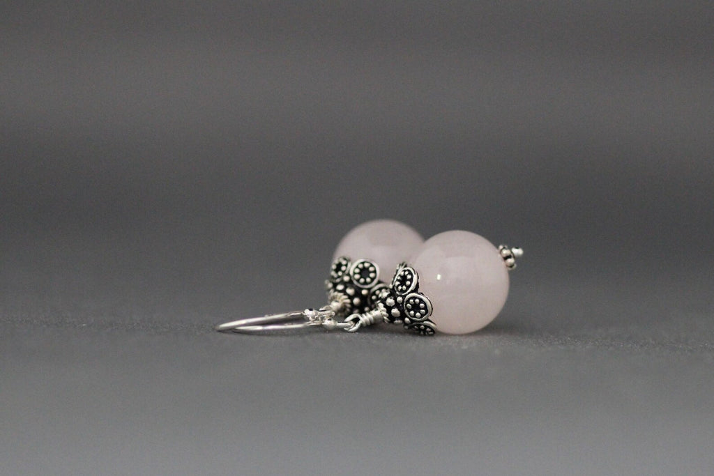 Rose quartz and silver earrings against a gray backdrop